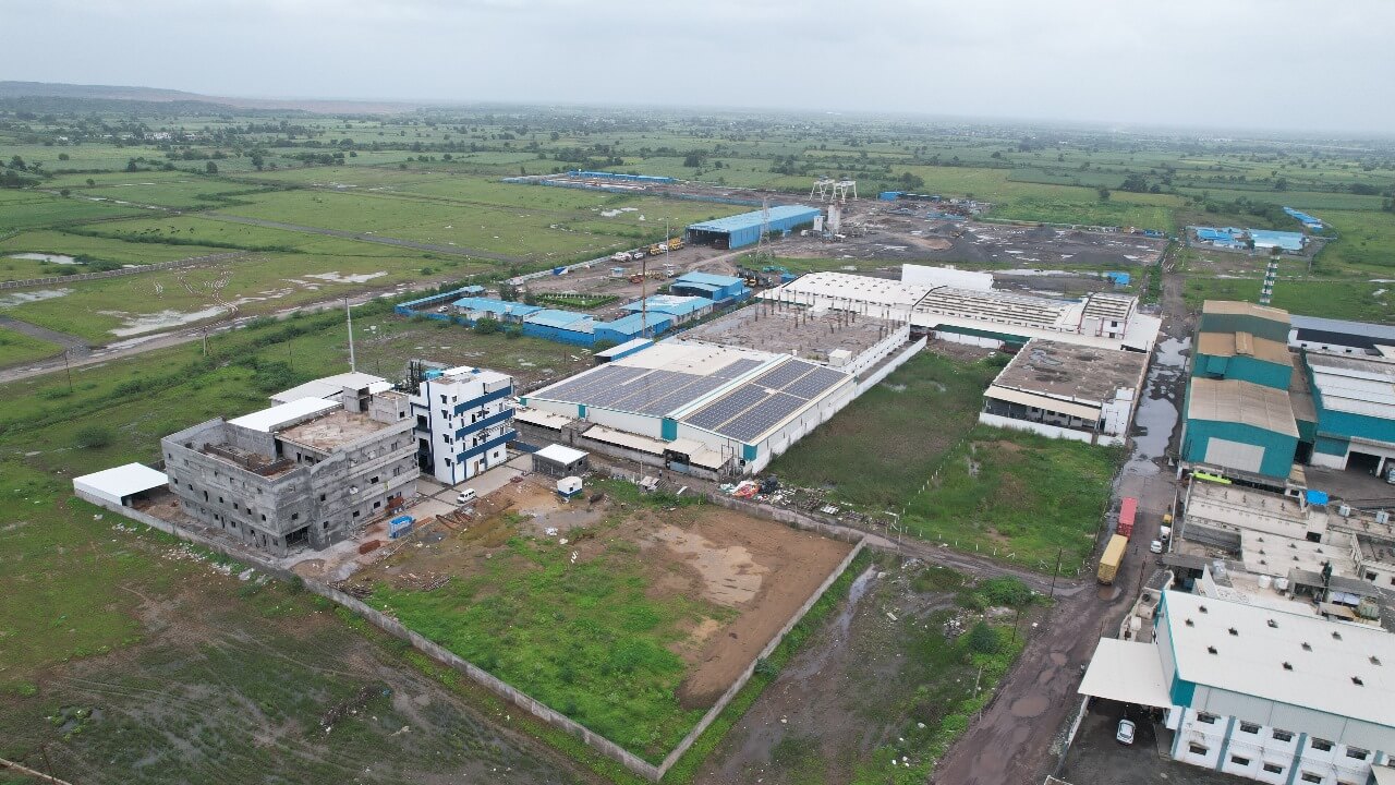 Panoramic drone shot of an Nipun industrial complex with rooftop solar panels and green fields