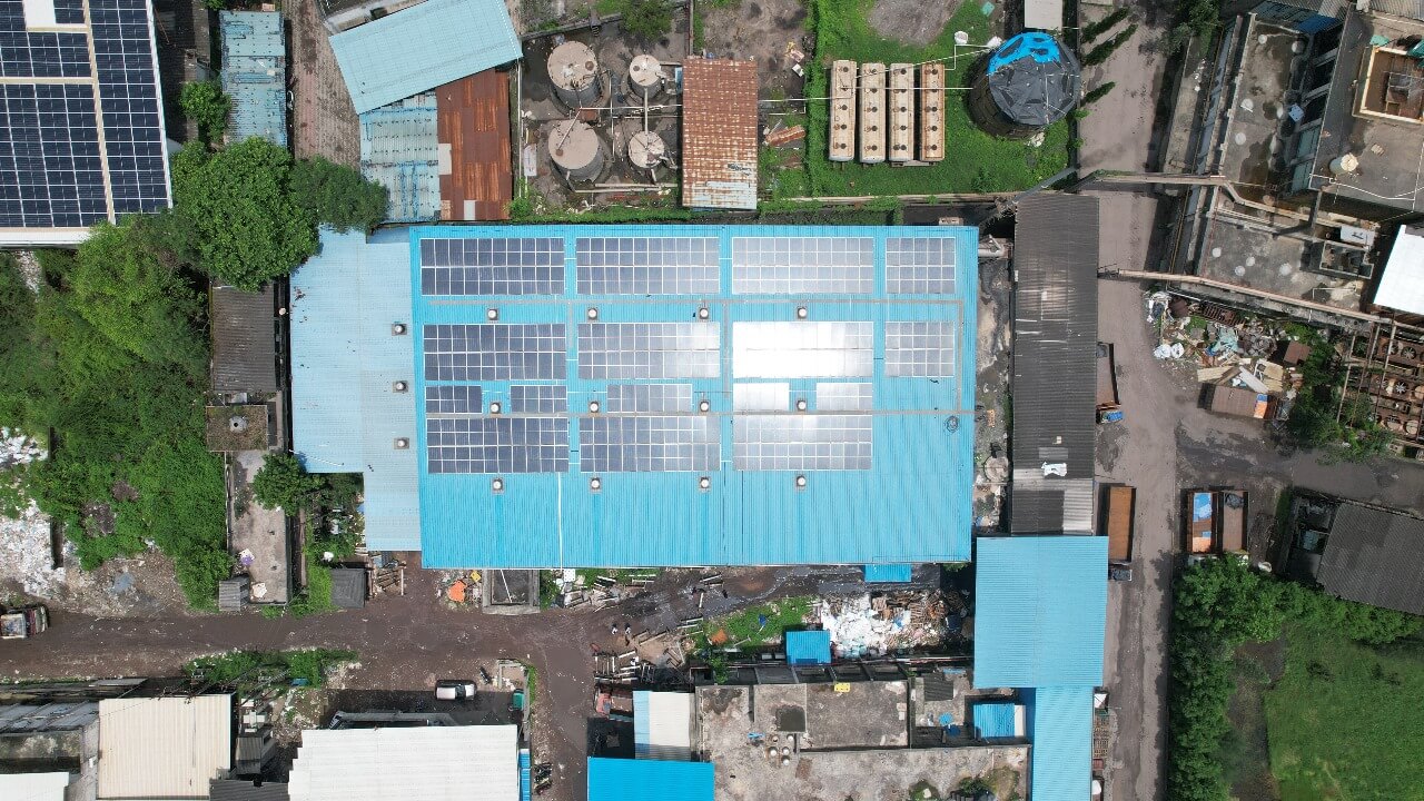 Overhead view of solar panels on a bright blue corrugated metal roof amidst storage tanks at Zab Sizer