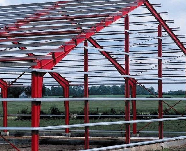 The steel frame structure of a pre-engineered building (PEB) during assembly on a construction site.